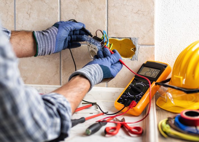 Electrician at work with the tester measures the voltage in the sockets of a residential electrical system. Construction industry.